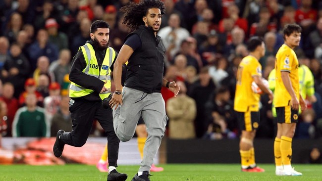 Penyusup lapangan rusak serangan Wolves yang sedang mengepung di depan kotak penalti Manchester United pada pertandingan Liga Inggris.