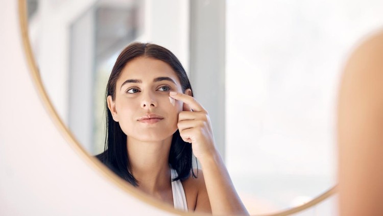 Mirror reflection of woman with skincare cream, spa lotion or dermatology ointment for melasma or acne treatment. Bathroom facial routine, healthcare and face of girl apply cosmetics beauty product