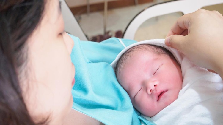 Pregnant young woman lying on the bed in delivery room. Side view of happy pregnant female resting on bed in hospital ward. Healthcare and pregnancy concept