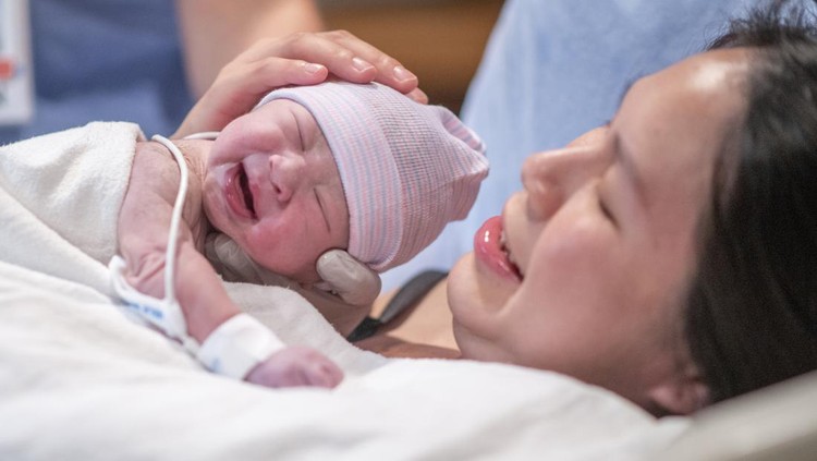 Pregnant young woman lying on the bed in delivery room. Side view of happy pregnant female resting on bed in hospital ward. Healthcare and pregnancy concept