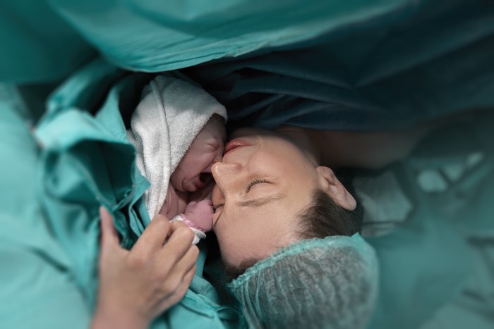 Pregnant young woman lying on the bed in delivery room. Side view of happy pregnant female resting on bed in hospital ward. Healthcare and pregnancy concept