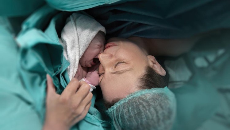 Pregnant young woman lying on the bed in delivery room. Side view of happy pregnant female resting on bed in hospital ward. Healthcare and pregnancy concept