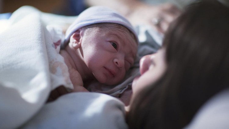 Pregnant young woman lying on the bed in delivery room. Side view of happy pregnant female resting on bed in hospital ward. Healthcare and pregnancy concept