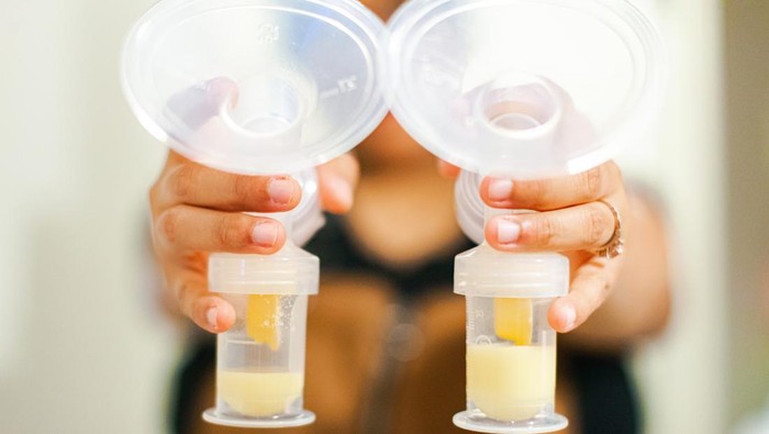 A mother proudly showing off the collection of breast milk from pumping.