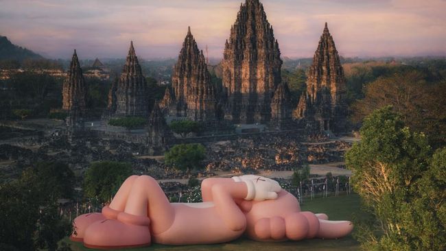 Patung ikonik karya seniman Brian Donelly alias KAWS kini hadir di Candi Prambanan, DI Yogyakarta selama periode 19-31 Agustus 2023.