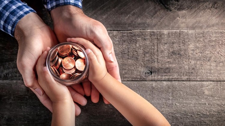 Hands Of Father Giving Jar Of Coins To Child On Wooden Table Background - Inheritance / Parent Providing For Children Concept