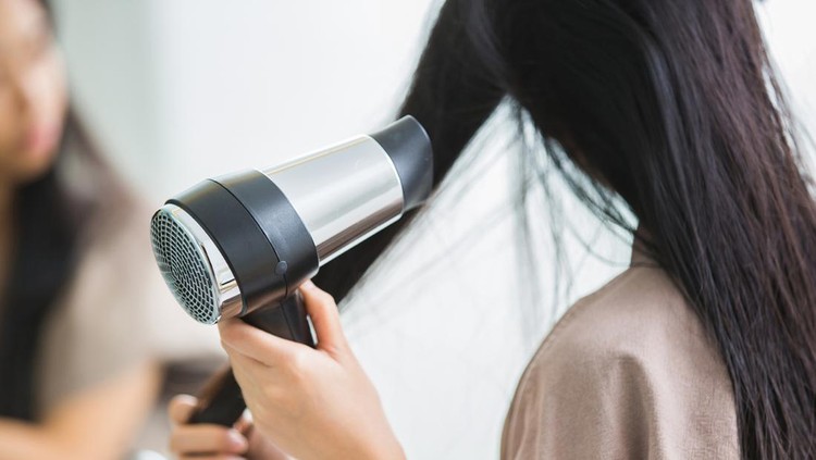 Woman with a hair dryer to heat the hair.