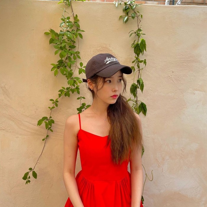 IU memadukan ball cap biru tua dengan gaya yang berbeda. Ia mengenakan dress merah tanpa lengan yang membuat tampilannya feminin namun tetap stylish./ Foto: vogue.co.kr