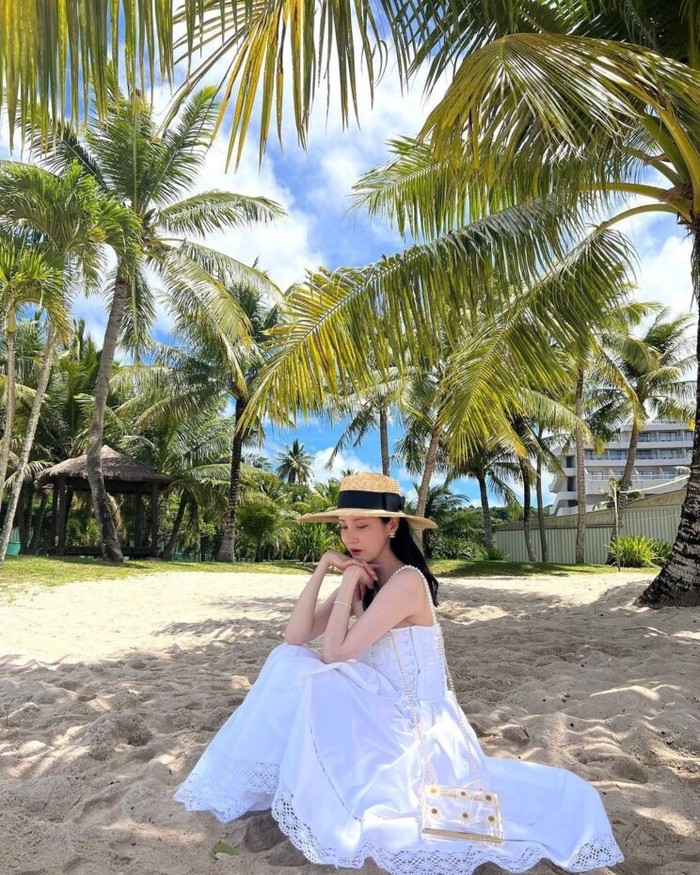 Seohyun melengkapi OOTD-nya mengenakan gaun tube top dan raffia hat dengan detail pita hitam yang feminin pada saat liburan. Tampilannya terlihat simple dan feminin, namun tetap stylish dan cantik./ Foto: vogue.co.kr