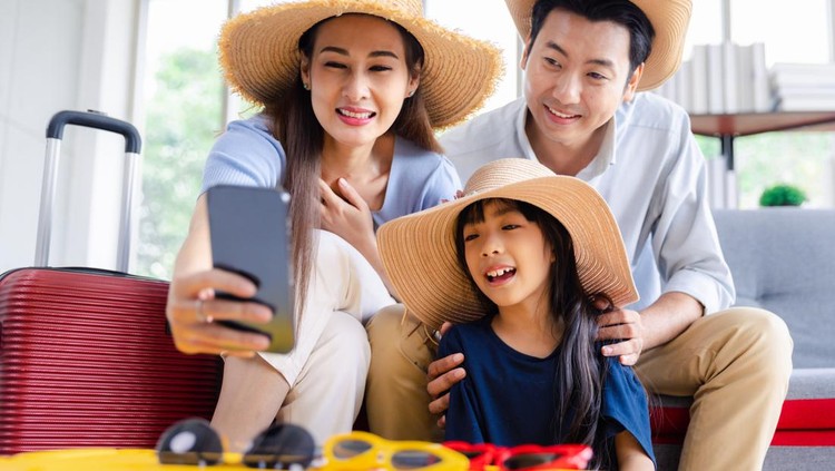 Young happy family asian father mother and daughter taking selfie photo exciting preparing luggage suitcase booking online ticket and hotel for vacation holiday travel trip