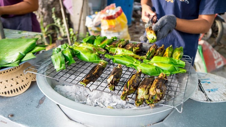 Delicious popular traditional Thai Asian style dessert food. Sticky rice toast with taro and banana leaf in Bang Nam Phueng Floating Market, Samut Prakan province, Thailand.