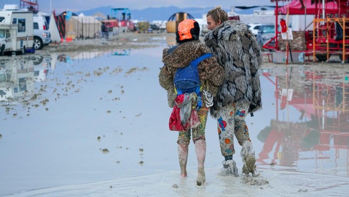 A Burning Man participant walks their bike through the mud near the exit, after a severe rainstorm left tens of thousands of revelers attending the annual festival stranded in mud in Black Rock City, in the Nevada desert September 3, 2023.  Trevor Hughes/USA Today Network via REUTERS.   MANDATORY CREDIT. NO RESALES. NO ARCHIVES