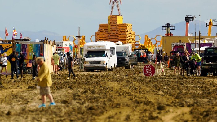 A Burning Man participant walks their bike through the mud near the exit, after a severe rainstorm left tens of thousands of revelers attending the annual festival stranded in mud in Black Rock City, in the Nevada desert September 3, 2023.  Trevor Hughes/USA Today Network via REUTERS.   MANDATORY CREDIT. NO RESALES. NO ARCHIVES
