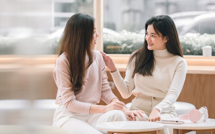 Asian beautiful women smiling and talking together in coffee shop. Lifestyle and Winter Concept.