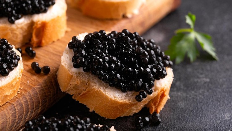 1370775170 Slices of bread with black caviar on rustic dark background.