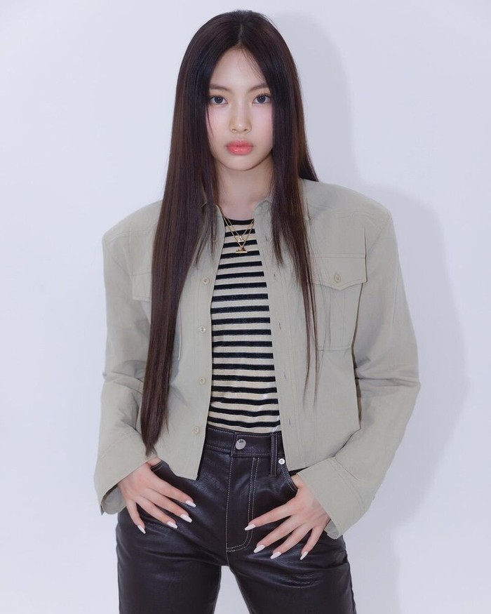 Hyein memadukan kaus stripes dengan jaket warna senada sehingga terlihat put together. Sedangkan celana faux leather hitam memberikan kesan edgy yang tak berlebihan./ Foto: Instagram/newjeans_official