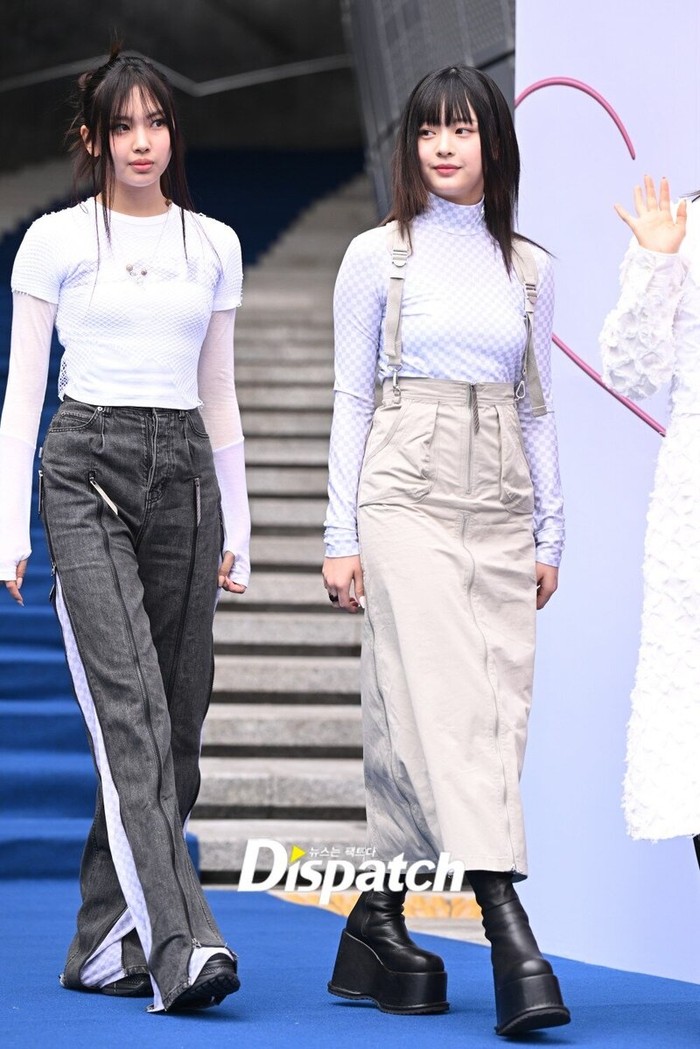 Tampil chic saat hang out dengan memakai overall skirt yang dipadu turtleneck lengan panjang ala Hanni. Kamu juga bisa memakai statement pants dengan kaus dan manset lengan panjang ala Hyein./ Foto: Dispatch