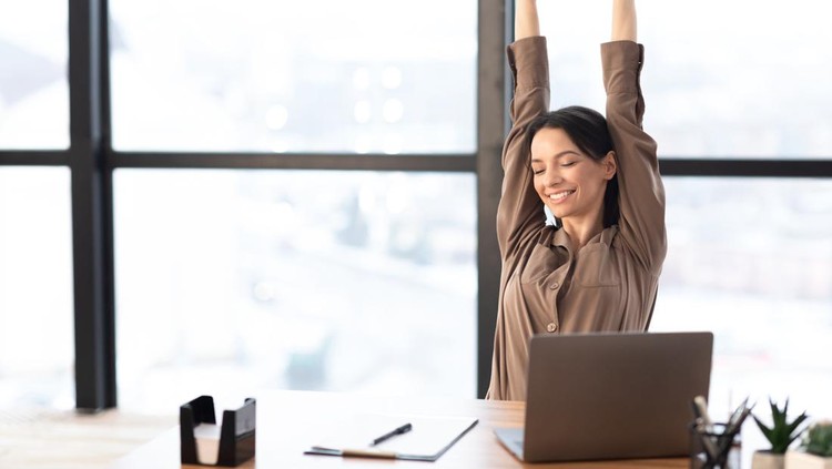 Good Morning. Happy female manager stretching her body and arms working at home or modern office, copyspace