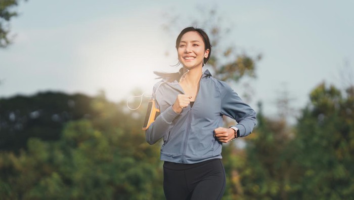 Healthy Asian woman is jogging outdoor. Fitness girl running. Female exercising at outdoor park.