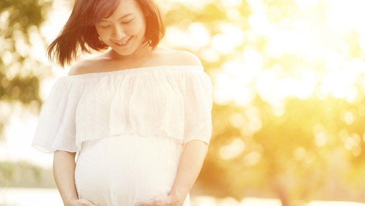 ilustrasi hamil Pregnant woman touching her big belly and walking in the park
