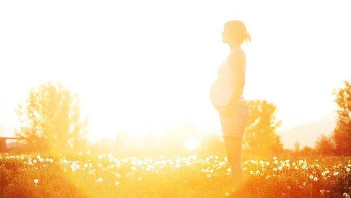 Pregnant woman touching her big belly and walking in the park