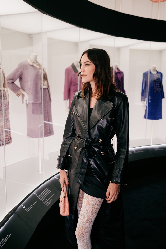 OOTD black & white Alexa Chung jauh dari kata monoton. Ia justru tampil eksentrik dengan trench coat leather yang berpadu stoking lace. / Foto: Courtesy of Chanel/ Oliver Holms
