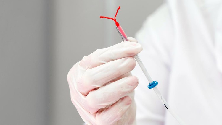 Holding an IUD birth control copper coil device in hand, used for contraception - front view