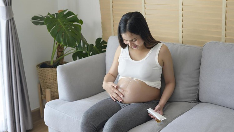 skincare ibu hamil Young pregnant woman applying moisturizing cream on tummy, healthcare and pregnancy care