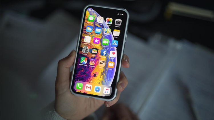 1059636822 Celje, Slovenia - October 07, 2018: Woman holding new iPhone XS smartphone (with protective VRS design case, 5.8 inch Retina display, silver color version with 256 GB memory) in her hand over the note pad.