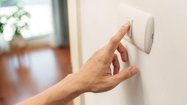 Closeup of finger is turning off on lighting switch on white wall at home. Power, Energy, Saving Electrical, Copy space.