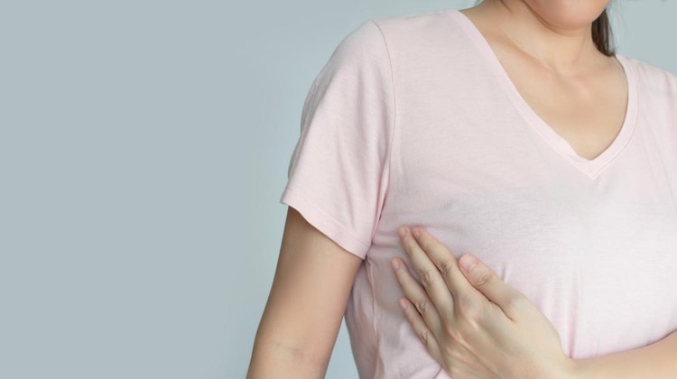 Asian woman is raise hand touch her breast to check cancer  to encourage breast cancer patient and support breast cancer campaign in October month
