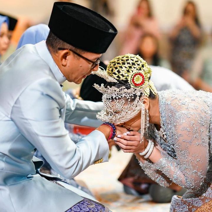 <p>Setelah ijab kabul, Atheera dan Panji melakukan sungkem pada Sandiaga dan isti. Dalam potret yang dibagikan, Sandiaga terlihat memegang pundah putrinya yang sedang mencium tangan sang ayah. Suasana haru nampak menyelimuti akad nikah sang putri, digelar dalam suasana yang intimate. (Foto: Instagram @sandiuno) (Foto: Instagram @sandiuno)</p>