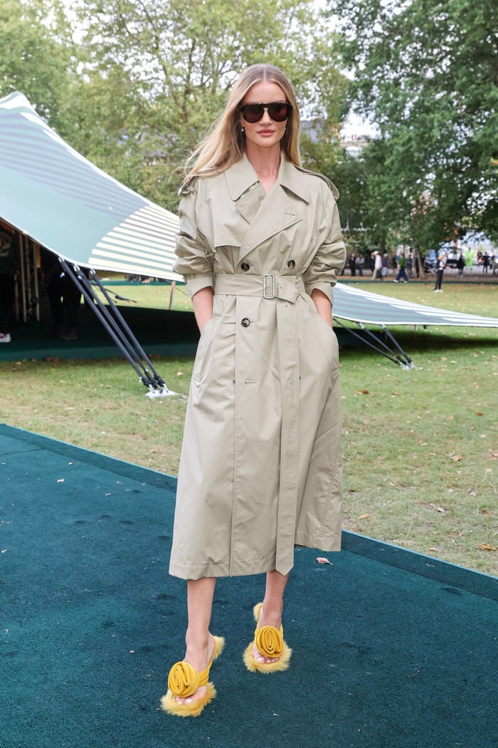 Rosie Huntington-Whiteley memancarkan nuansa santai dan outdoorsy. Cukup mengenakan trench coat ikonis Burberry, sang model buat gayanya lebih bold dengan mules aksen bulu dan mawar. Foto: Dave Benett/Dave Benett