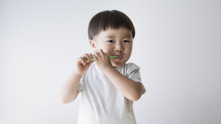An asian boy brushing his teeth.