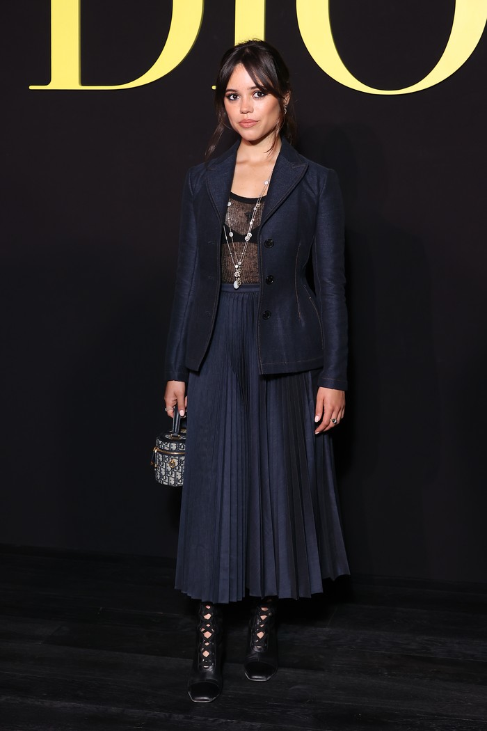 Membawa signature gothic ke Paris Fashion Week dalam tampilan ala Wednesday Adams. Dior blazer dipasangkan dengan pleated skirt berwarna biru tua yang senada./ Foto: WireImage/Marc Piasecki