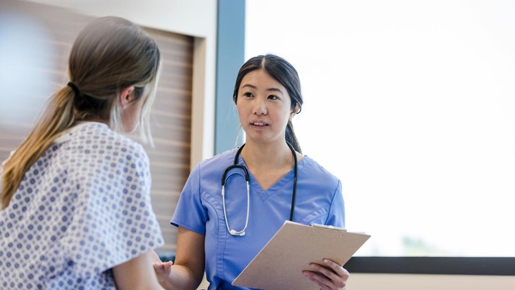 At the hospital, the mid adult female doctor gives her young adult female patient the good news from her medical tests.