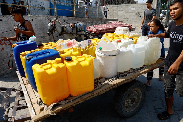 People stand next to containers as Palestinians gather to fill water from public taps amid the conflict with Israel in Khan Younis, in the southern Gaza Strip, October 11, 2023. REUTERS/Ibraheem Abu Mustafa