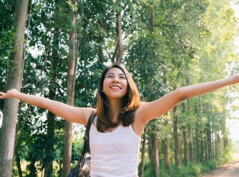 Perempuan berjalan sambil merentangkan tangan dan tersenyum