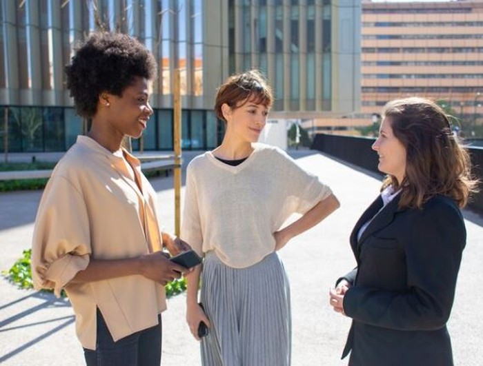 Tiga orang sedang mengobrol sambil berdiri