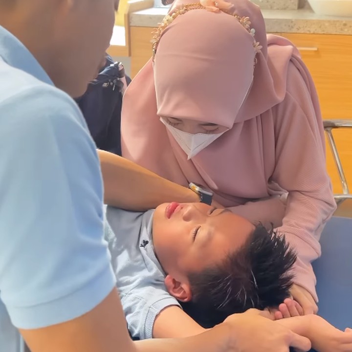 <p>Beberapa waktu lalu, Ikram turut mendampingi Yusuf untuk melakukan khitan. Ia memegang tangan sang anak seraya menenangkan Yusuf yang tengah menangis. (Foto: Instagram: @larissachou)</p>