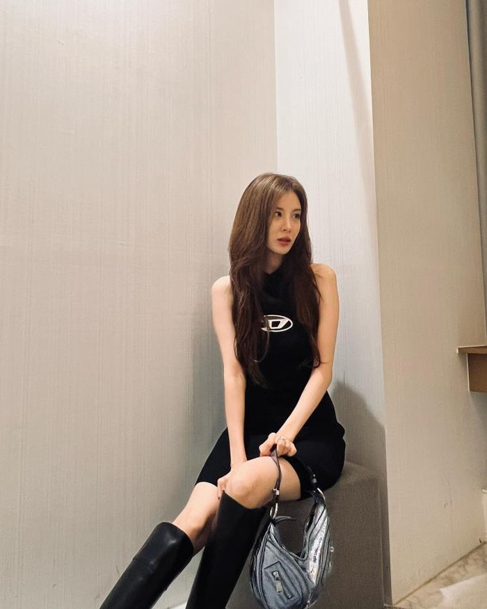Girls' Generation's Seohyun emphasizes her body lines in a body-fitting black dress with a Diesel logo decoration on the chest.  She combined it with long boots and a metallic bag to complete the look of the Y2K version of the dress./ Photo: elle.co.kr