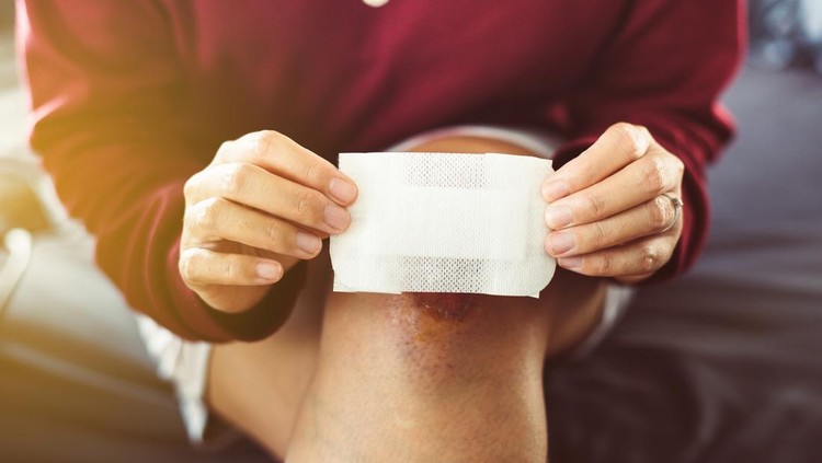 Woman using white patch for relieve wound on knee,Elastic bandaged