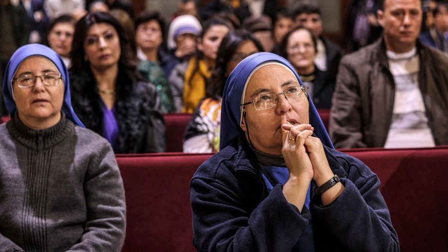 Suster Mara del Pilar (kiri) dan Suster Mara del Perpetuo Socorro (kanan) dipotret pada sebuah ibadah Natal di Gereja Katolik di Gaza pada Desember 2022 (Photo by MAHMUD HAMS / AFP) (Photo by MAHMUD HAMS/AFP via Getty Images)