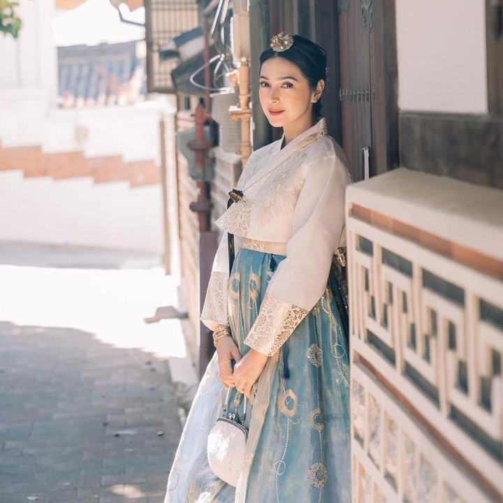 <p>Hanbok yang ia kenakan ini berlengan panjang dan didominasi dengan warna biru, putih dan gold. Tak hanya itu, tampilannya dilengkapi dengan tas tangan dan hiasan kepala. (Foto: Instagram: @nsyakieb85)</p>