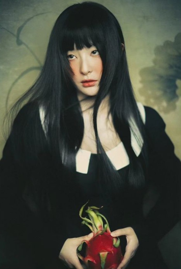 Bagai lukisan, Seulgi tampil tak kalah cantik dengan tatapan misterius. Buah naga di tangannya begitu mencolok, seakan menyimpan makna tersirat/Foto: instagram.com/redvelvet.smtown