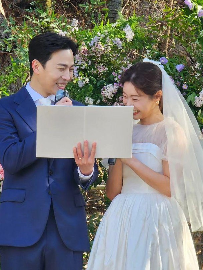 Sojin tampak cantik dalam balutan wedding gown dan wedding veil berwarna putih, sementara Lee Dong Ha tampil penuh karisma dalam balutan wedding suit berwarna navy./ Foto: soompi.com