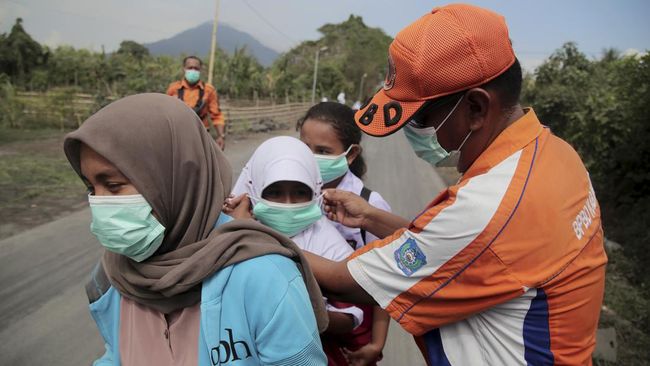 Petugas Badan Penanggulangan Bencana Daerah (BPBD) memasangkan masker kepada siswa SD yang terdampak abu vulkanik Gunung Dukono di Desa Gorua, Kecamatan Tobelo Utara, Kabupaten Halmahera Utara, Maluku Utara, Senin (20/11/2023). Pembagian masker untuk
