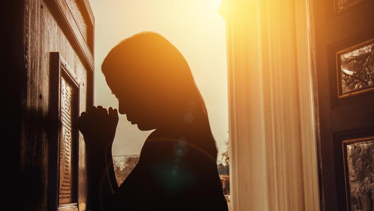 Doa Katolik silhouette of woman kneeling and praying in modern church at sunset time