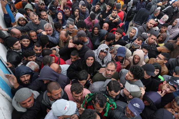 A Palestinian woman presents her ration card to receive flour bags distributed by the United Nations Relief and Works Agency (UNRWA) during a temporary truce between Hamas and Israel, in Khan Younis in the southern Gaza Strip November 27, 2023. REUTERS/Ibraheem Abu Mustafa