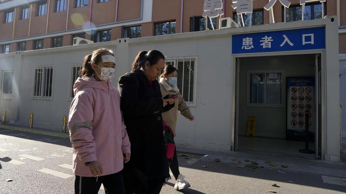 Residents wearing masks pass by a children's hospital in Beijing, Friday, Nov. 24, 2023. Chinese officials say they did not detect any 